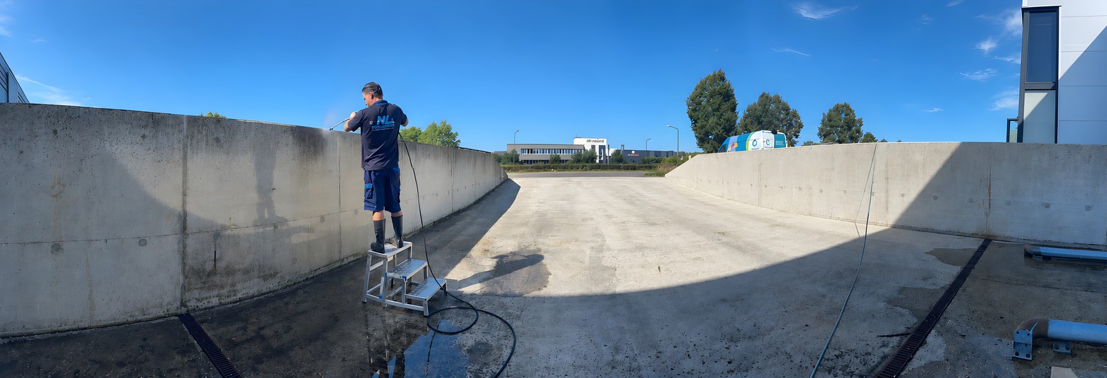 Medewerker van NL Reiniging reinigt een laaddockmuur met hogedrukreiniger